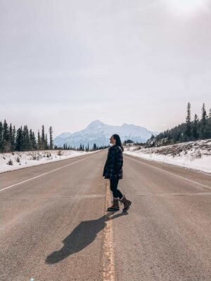 Travelling solo in Banff, Canada. Standing in the middle of the road, admiring the mountains in the background. 