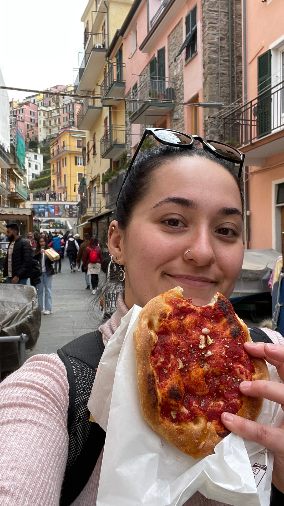 Amid the charming streets of Cinque Terre, a contented figure holds a mouthwatering panini, a true delight for the senses. The colorful architecture forms a vibrant backdrop as the person's satisfied expression mirrors the savory joy of their meal. A perfect moment of culinary indulgence against the picturesque backdrop of this Italian coastal gem.